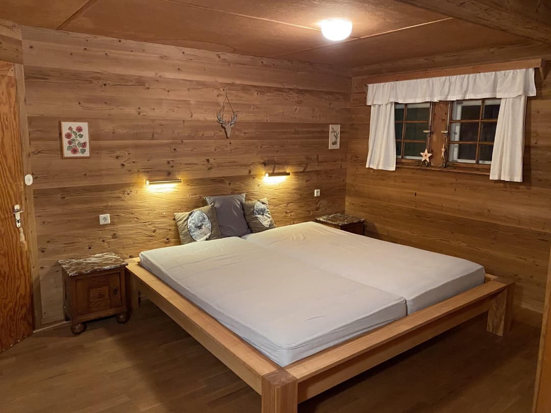 Mittleres Doppelbett mit weißem Bezug und Nachtischen mit Beleuchtung