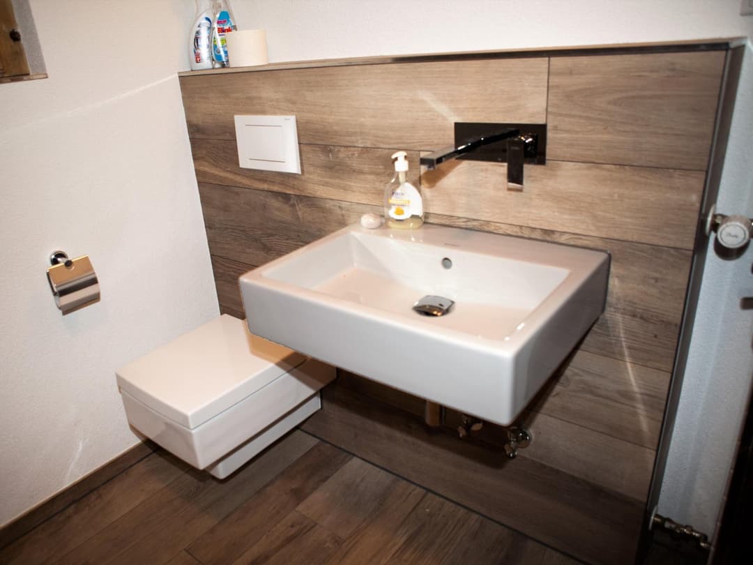 Weißes Porzellanwaschbecken mit einem WC links